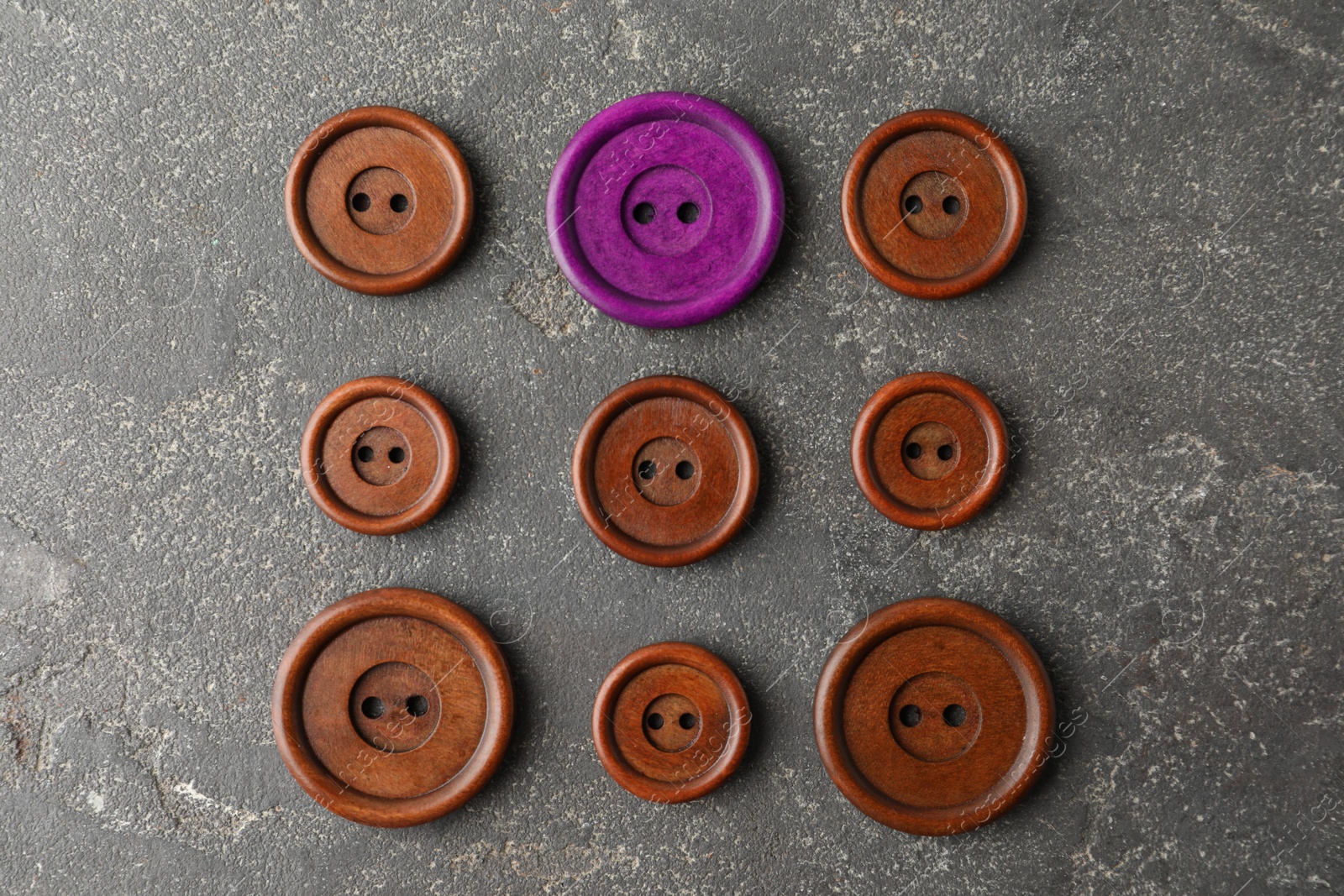 Individuality, uniqueness, different. Purple sewing button among brown ones on grey textured background, flat lay Image of Individuality, uniqueness, different. Purple sewing button among brown ones on grey textured background, flat lay
