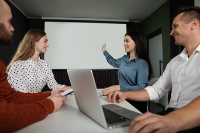 Photo of Business people having meeting in conference room with video projection screen