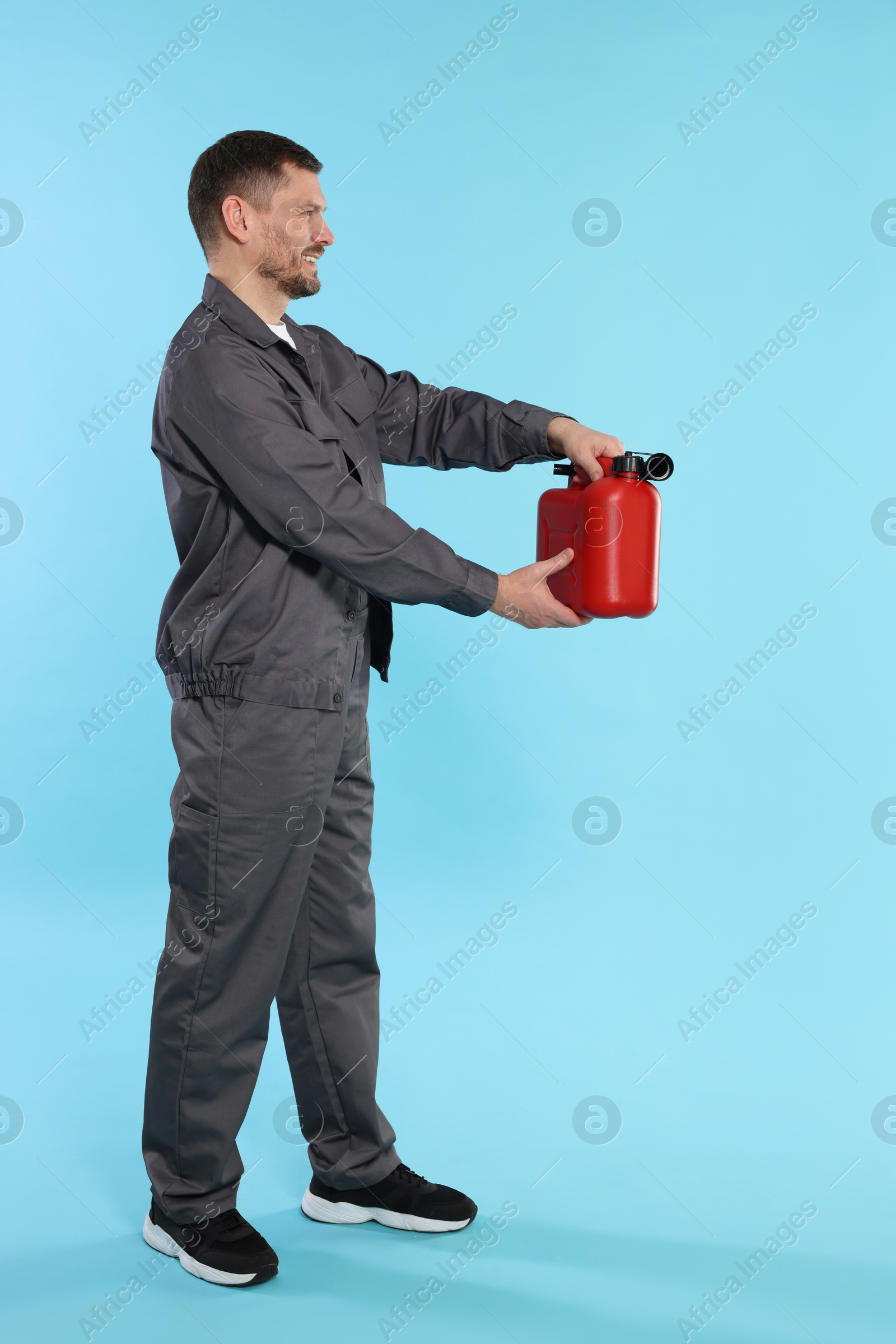 Man holding plastic canister on light blue background Photo of Man holding plastic canister on light blue background