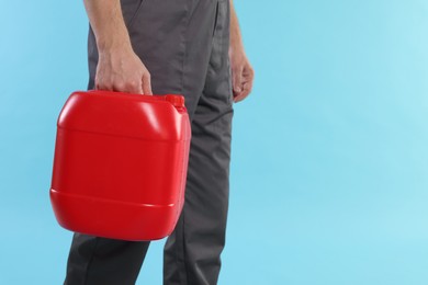 Photo of Man holding plastic canister on light blue background, closeup. Space for text