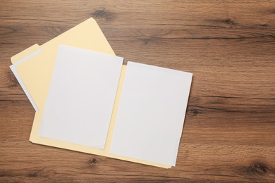 Photo of Paper file folders with blank sheets on wooden table, flat lay. Space for text