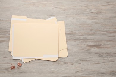 Photo of File folders with papers and binder clips on wooden table, flat lay. Space for text