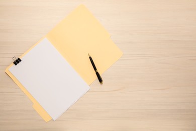 Photo of Paper file folder with blank sheet and pen on wooden table, top view. Space for text