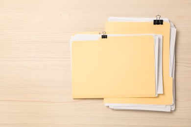 Photo of File folders with papers and binder clips on wooden table, top view. Space for text