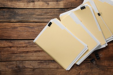Photo of File folders with papers and binder clips on wooden table, flat lay. Space for text
