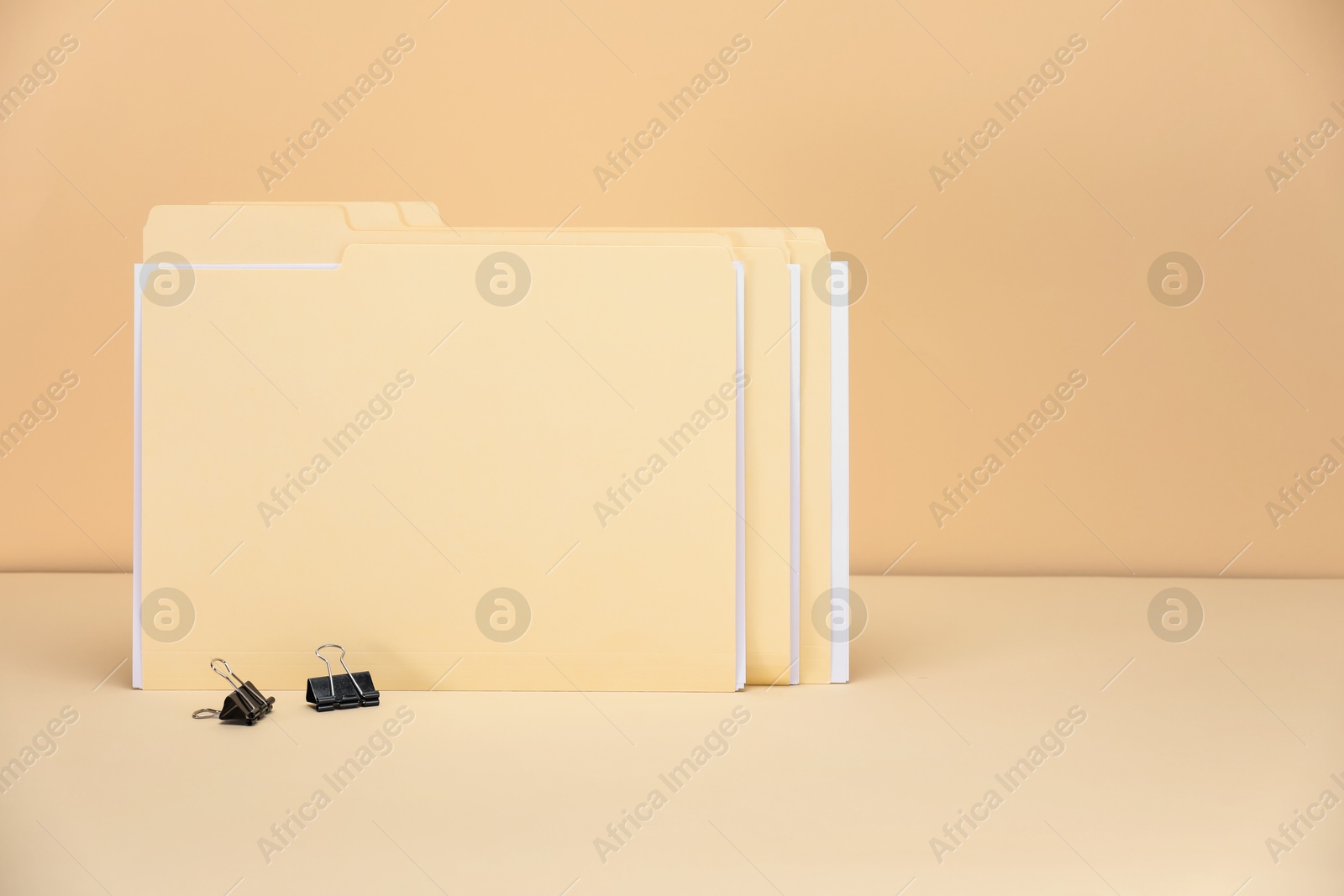 File folders with papers and binder clips on pale yellow background, space for text Photo of File folders with papers and binder clips on pale yellow background, space for text