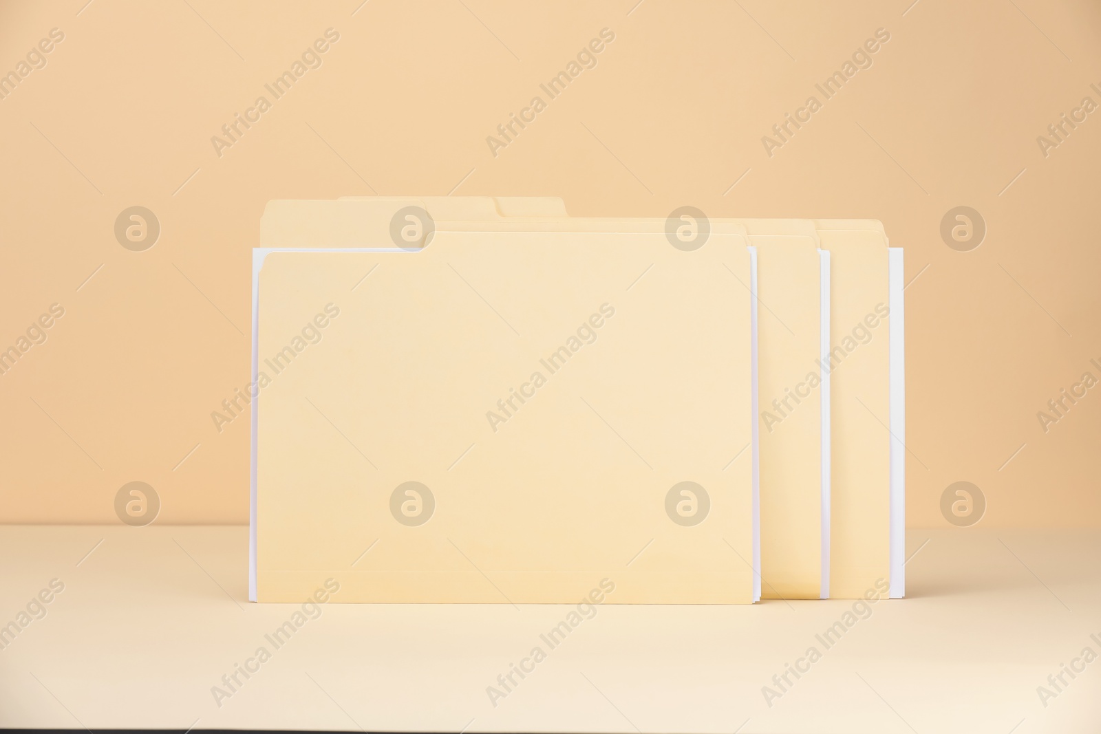File folders with papers on pale yellow background Photo of File folders with papers on pale yellow background