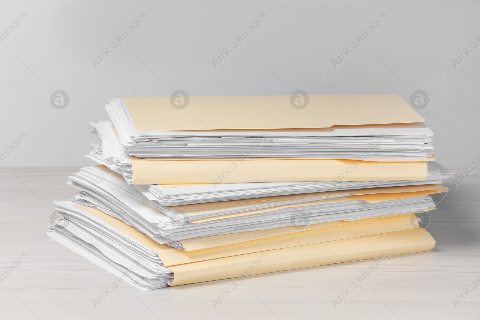 File folders with papers on wooden table against light background Photo of File folders with papers on wooden table against light background