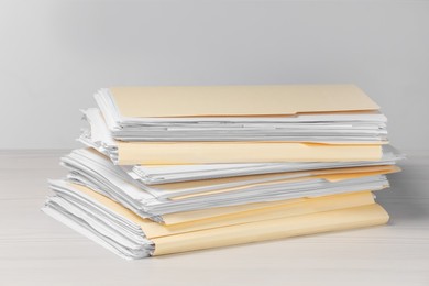 Photo of File folders with papers on wooden table against light background