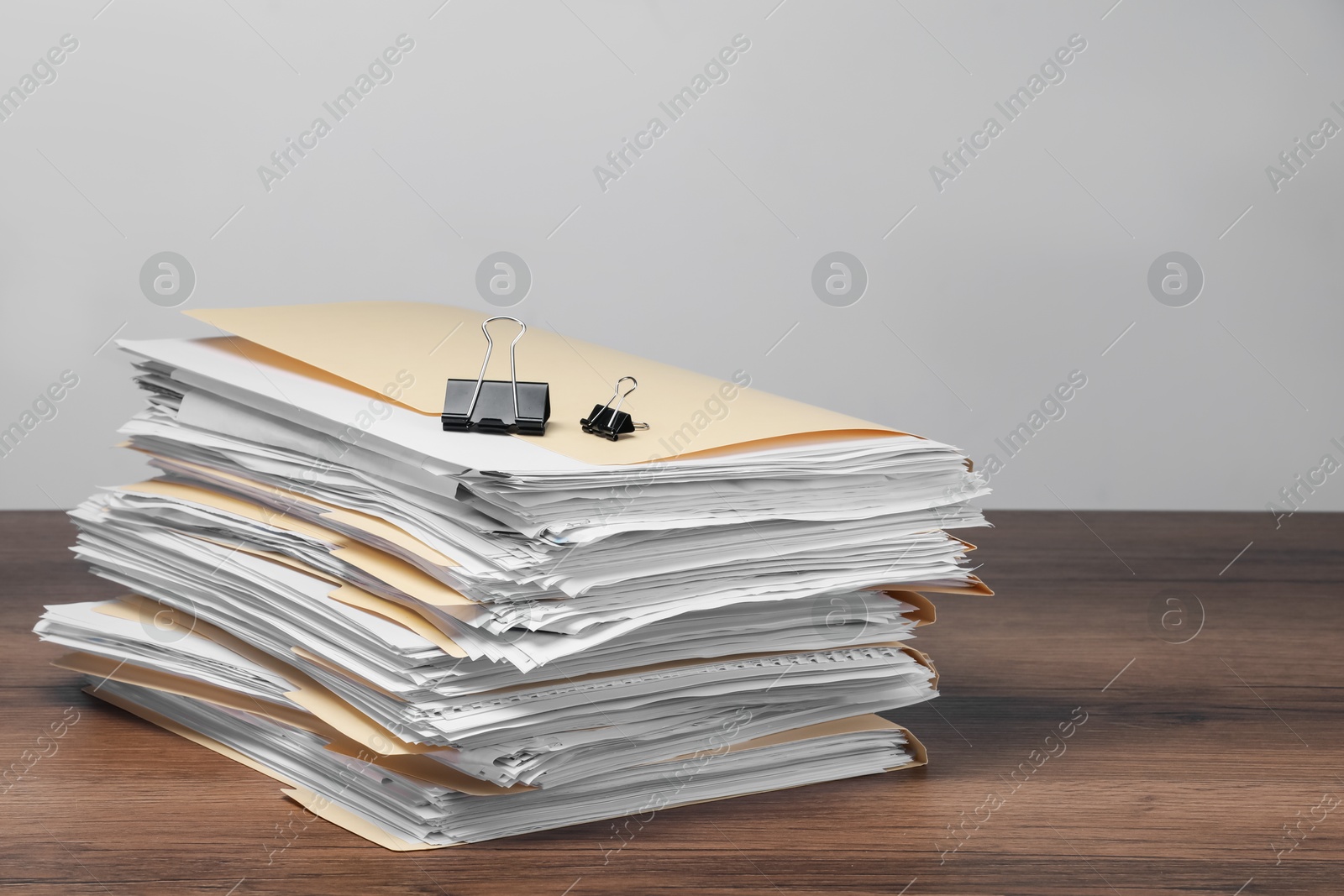 File folders with papers and binder clips on wooden table against gray background Photo of File folders with papers and binder clips on wooden table against gray background