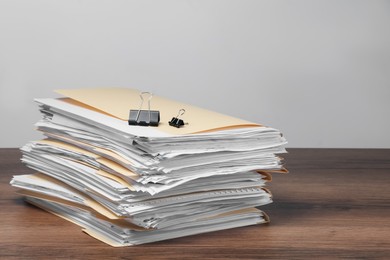 Photo of File folders with papers and binder clips on wooden table against gray background