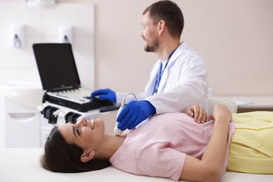 Photo of Sonographer conducting ultrasound examination of woman's thyroid gland in clinic