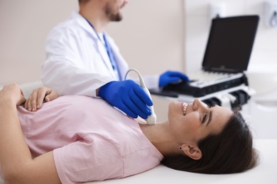 Photo of Sonographer conducting ultrasound examination of woman's thyroid gland in clinic, closeup