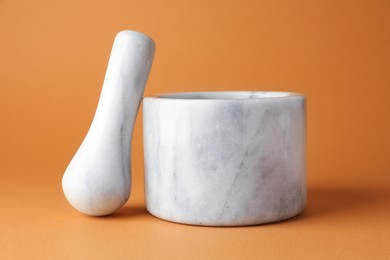 Photo of Marble mortar and pestle on light brown background, closeup
