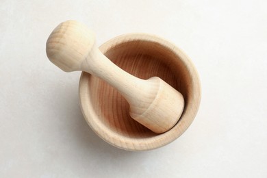 Photo of Wooden mortar and pestle on white table, top view
