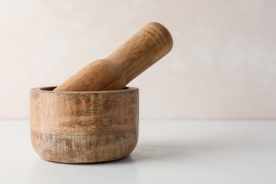Photo of Wooden mortar and pestle on white table, closeup. Space for text