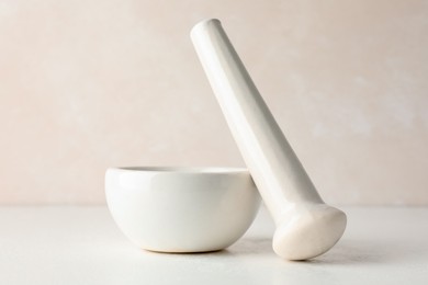 Photo of Ceramic mortar and pestle on white table, closeup