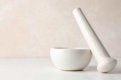Photo of Ceramic mortar and pestle on white table, closeup. Space for text