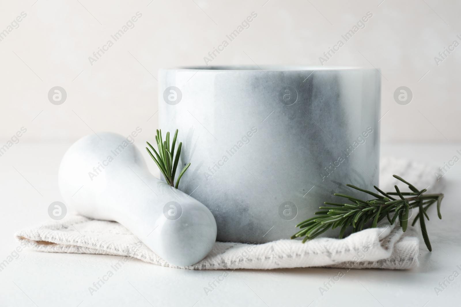 Marble mortar with rosemary, pestle and cloth on white table, closeup Photo of Marble mortar with rosemary, pestle and cloth on white table, closeup