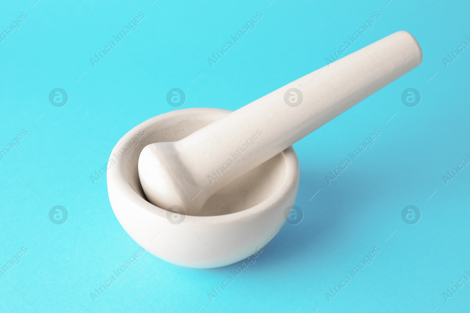 Ceramic mortar and pestle on light blue background, closeup Photo of Ceramic mortar and pestle on light blue background, closeup