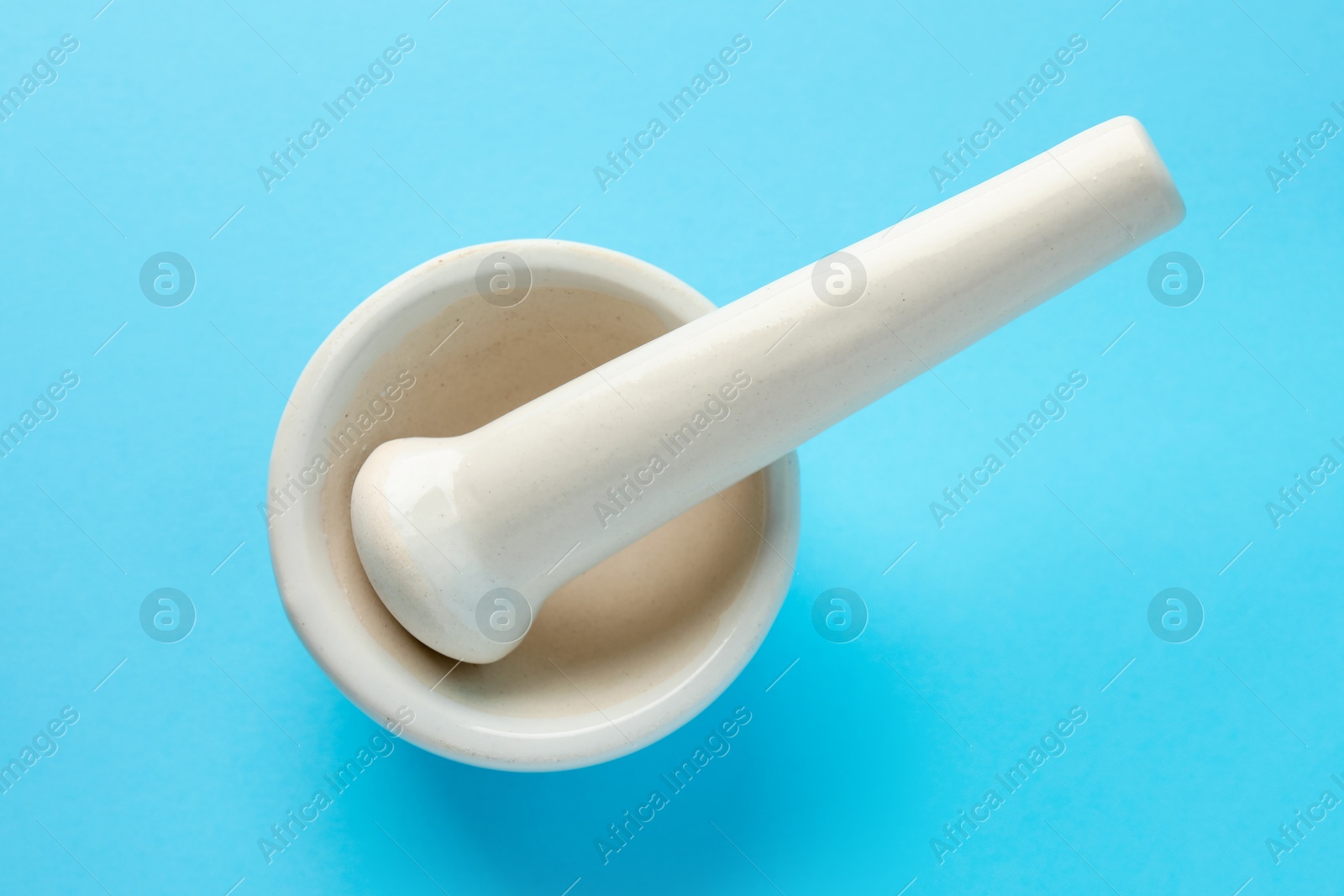 Ceramic mortar and pestle on light blue background, top view Photo of Ceramic mortar and pestle on light blue background, top view