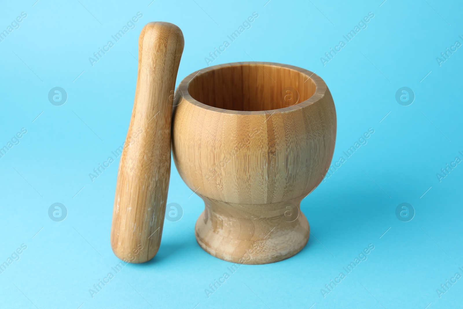 Wooden mortar and pestle on light blue background, closeup Photo of Wooden mortar and pestle on light blue background, closeup