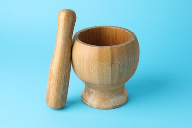 Photo of Wooden mortar and pestle on light blue background, closeup