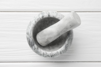 Photo of Marble mortar and pestle on white wooden table, top view