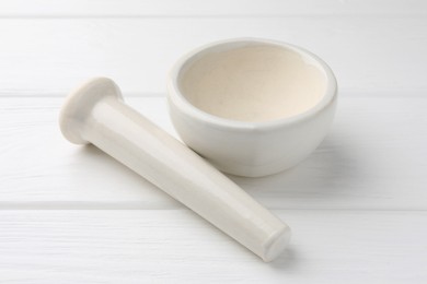 Photo of Ceramic mortar and pestle on white wooden table, closeup