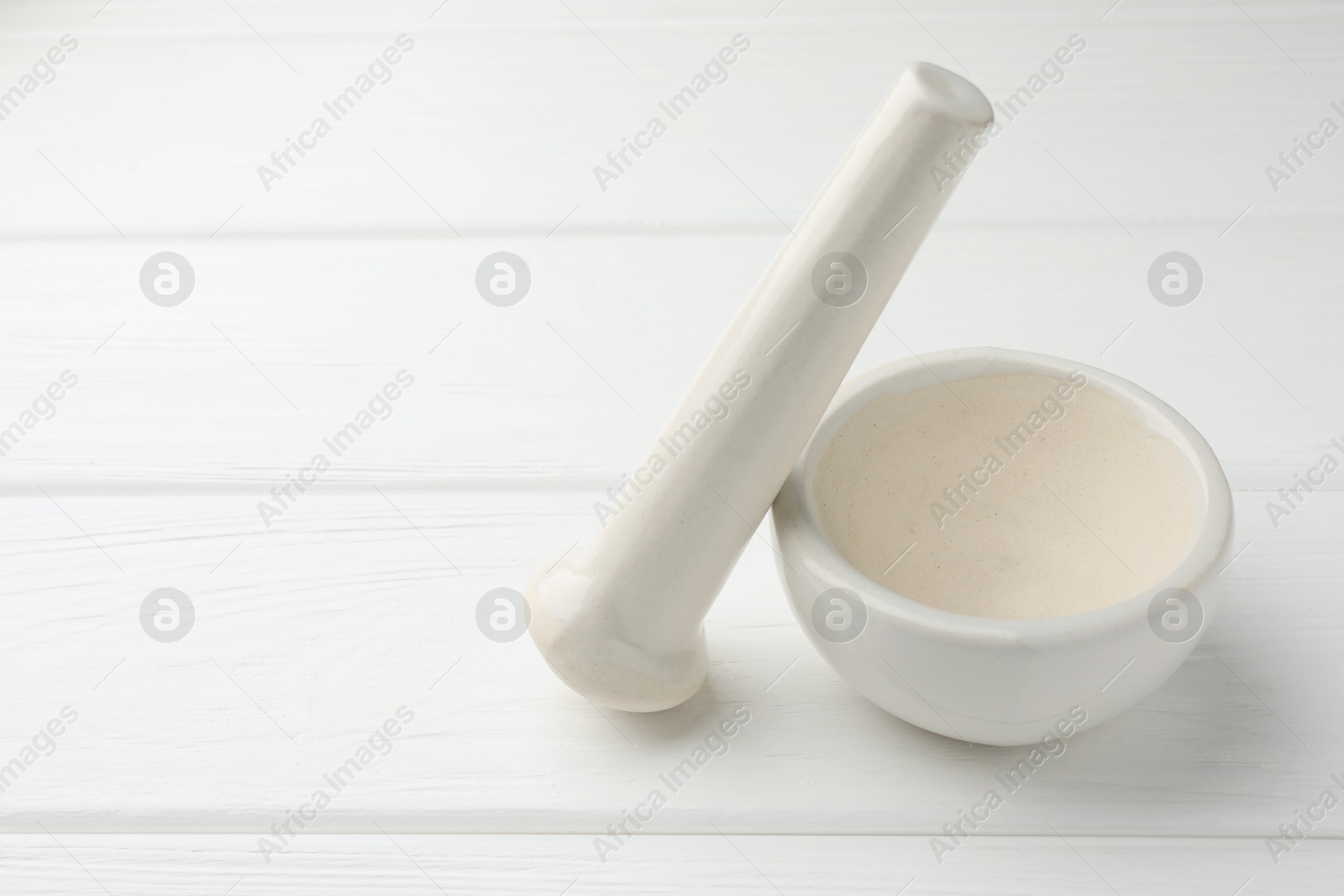 Ceramic mortar and pestle on white wooden table. Space for text Photo of Ceramic mortar and pestle on white wooden table. Space for text