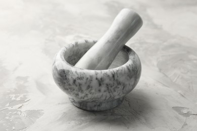 Photo of Marble mortar and pestle on grey textured table, closeup