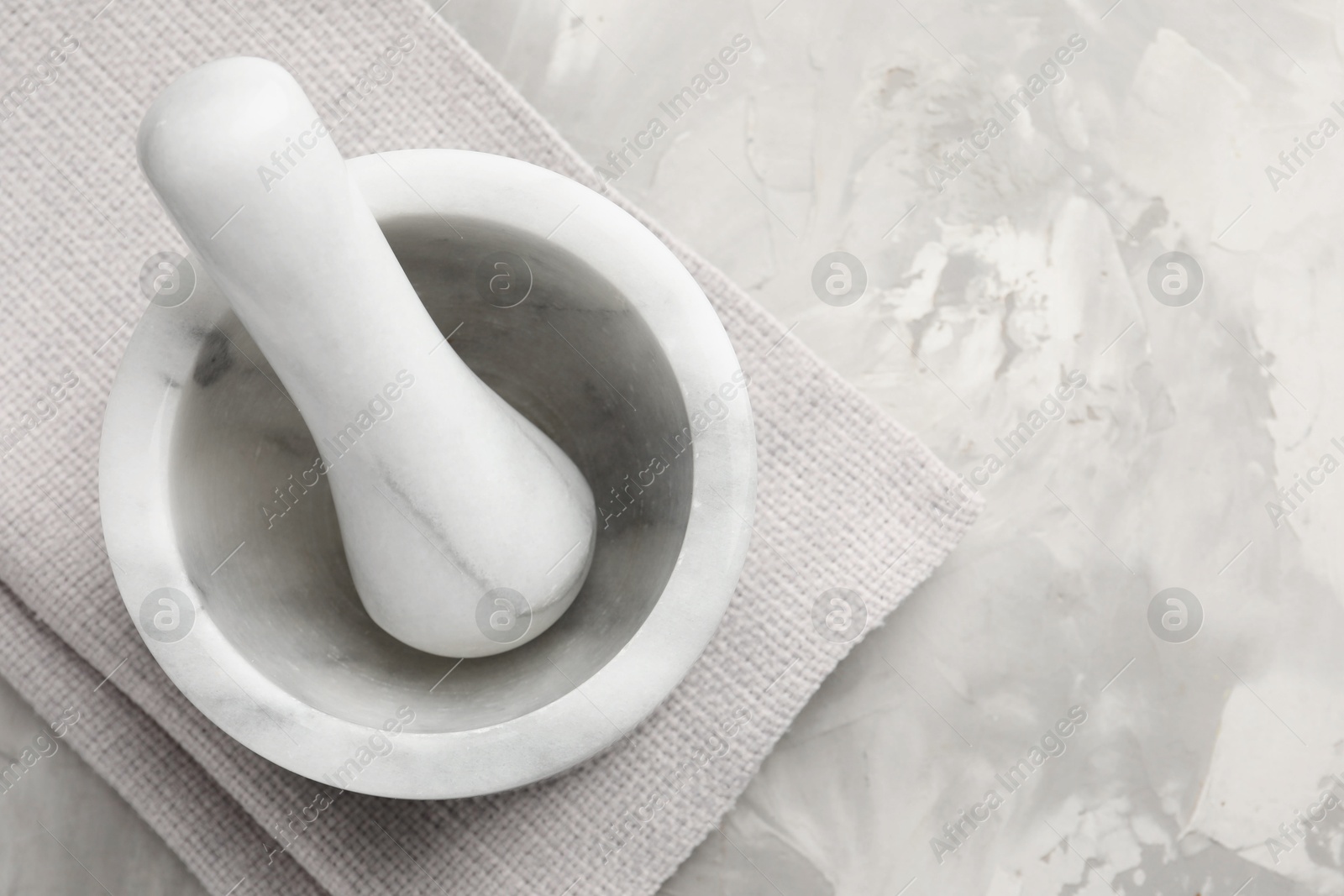 Marble mortar, pestle and cloth on grey textured table, top view. Space for text Photo of Marble mortar, pestle and cloth on grey textured table, top view. Space for text
