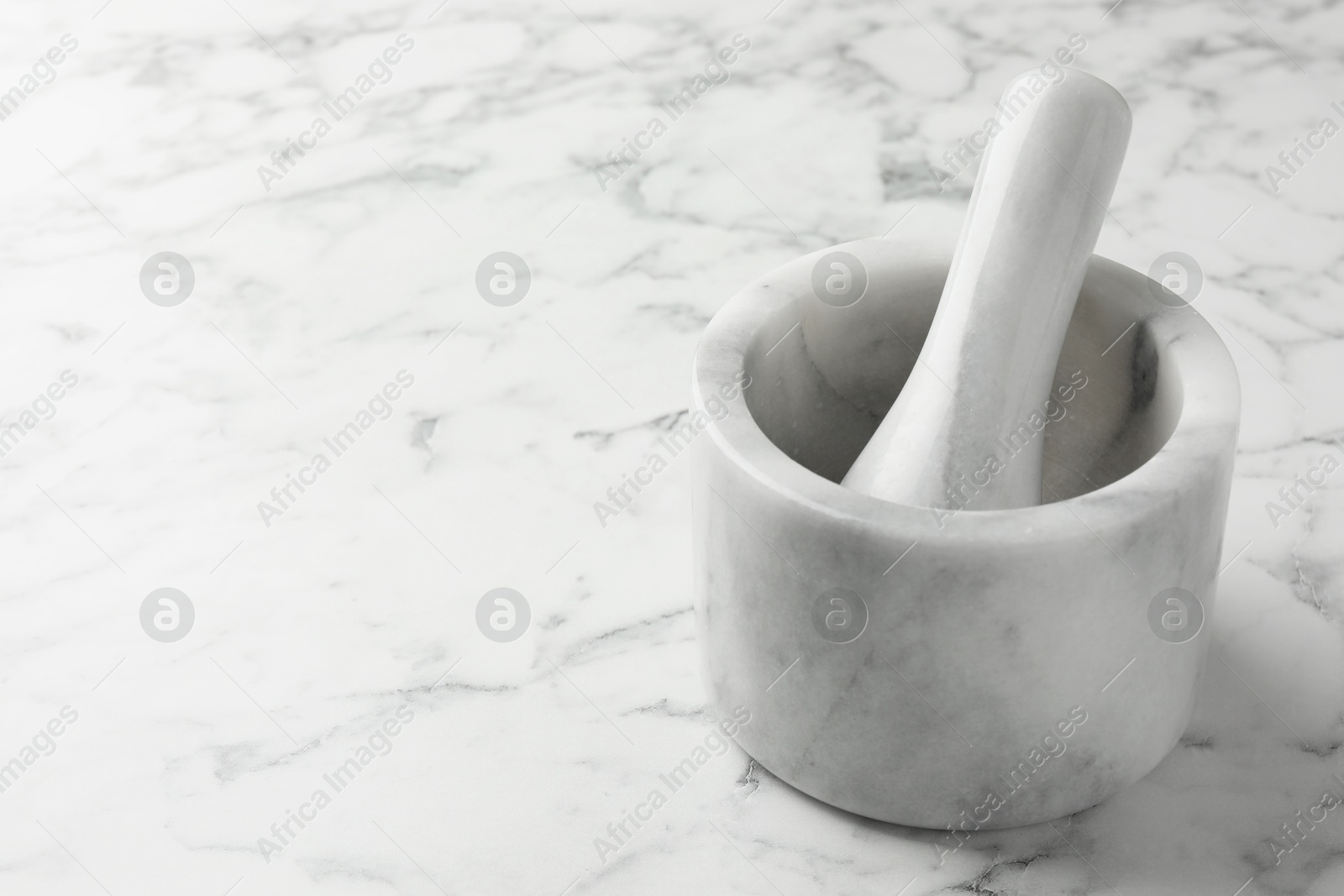 Mortar and pestle on white marble table, closeup. Space for text Photo of Mortar and pestle on white marble table, closeup. Space for text