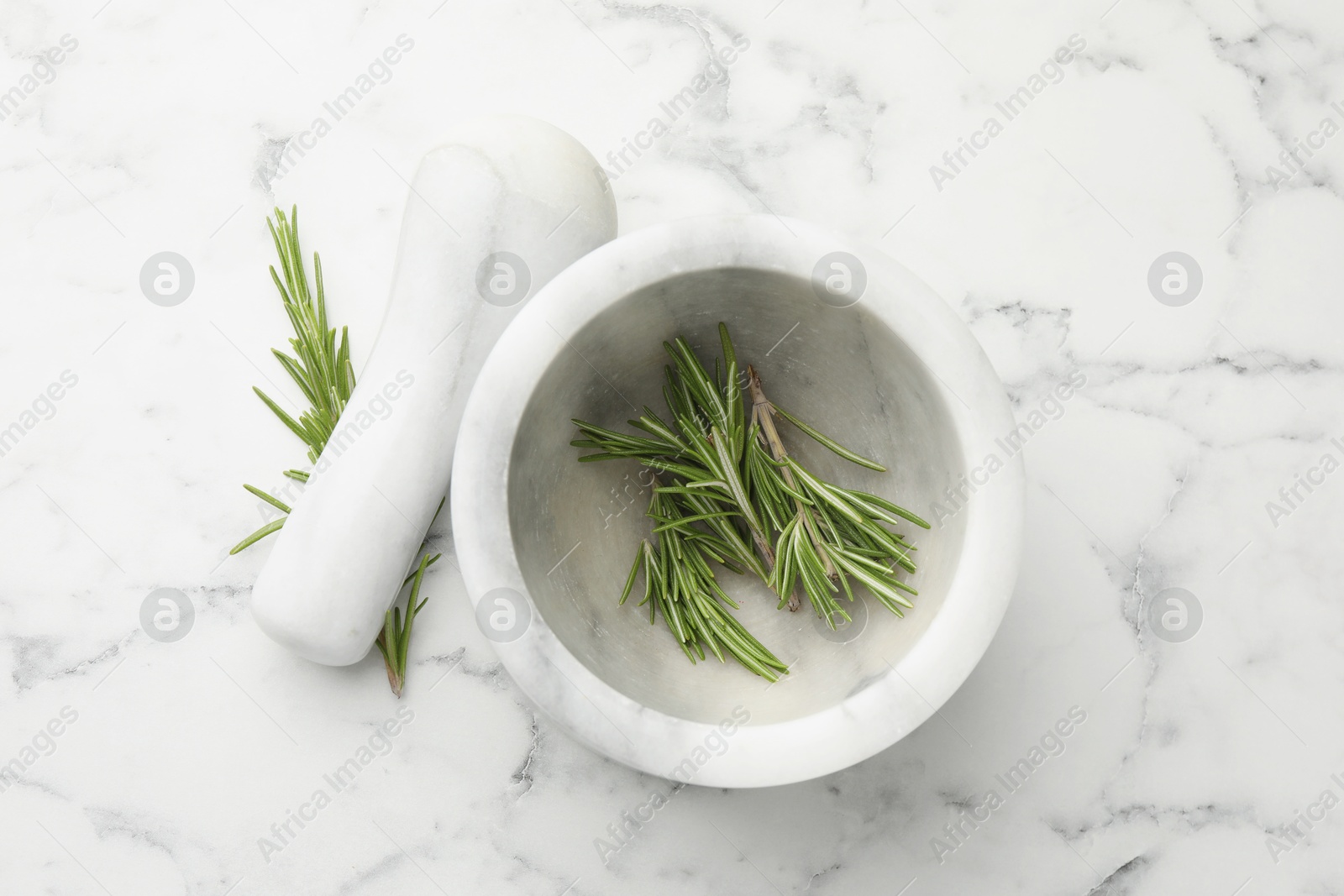 Mortar with rosemary and pestle on white marble table, flat lay Photo of Mortar with rosemary and pestle on white marble table, flat lay