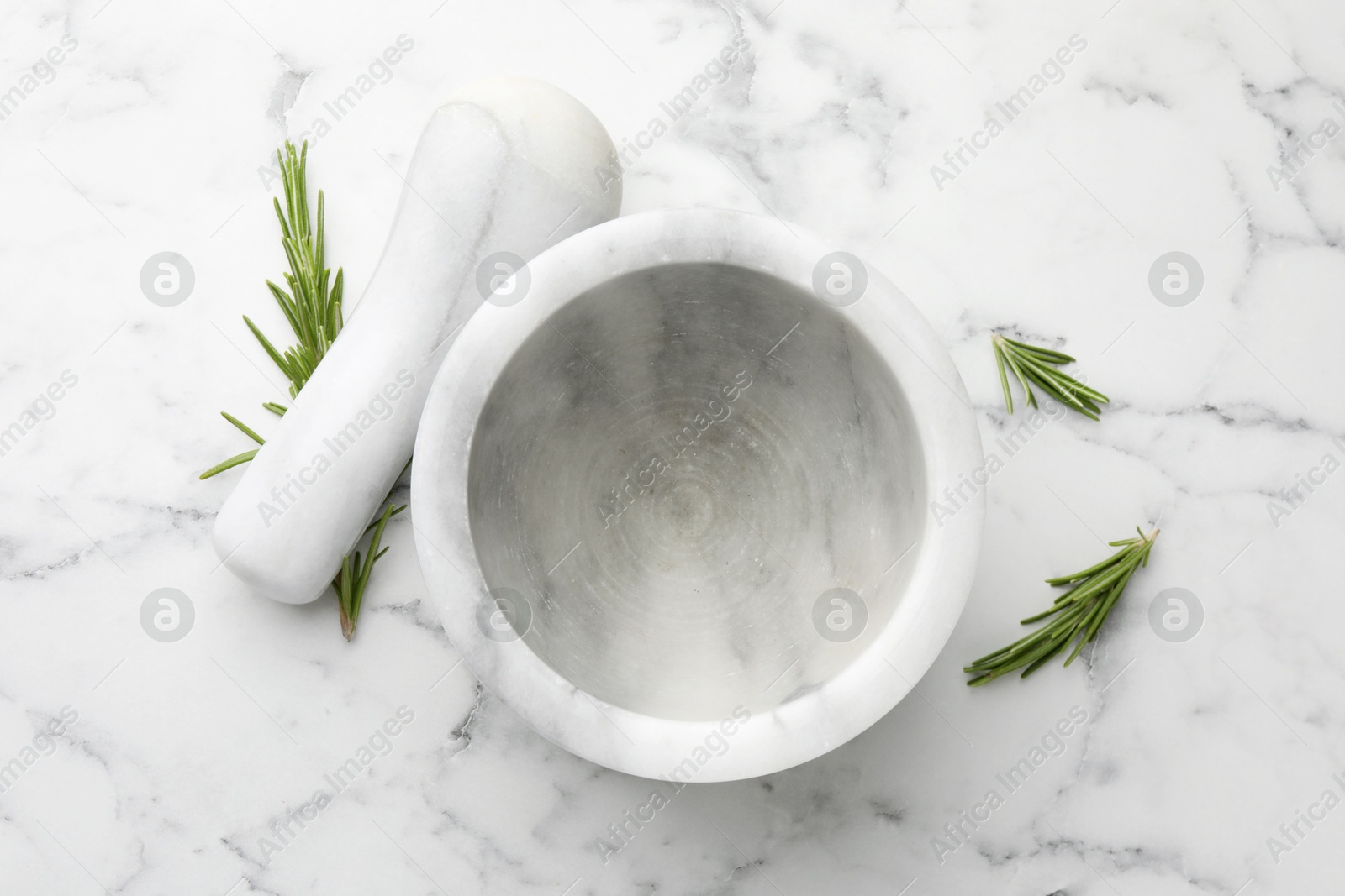 Mortar with rosemary and pestle on white marble table, flat lay Photo of Mortar with rosemary and pestle on white marble table, flat lay