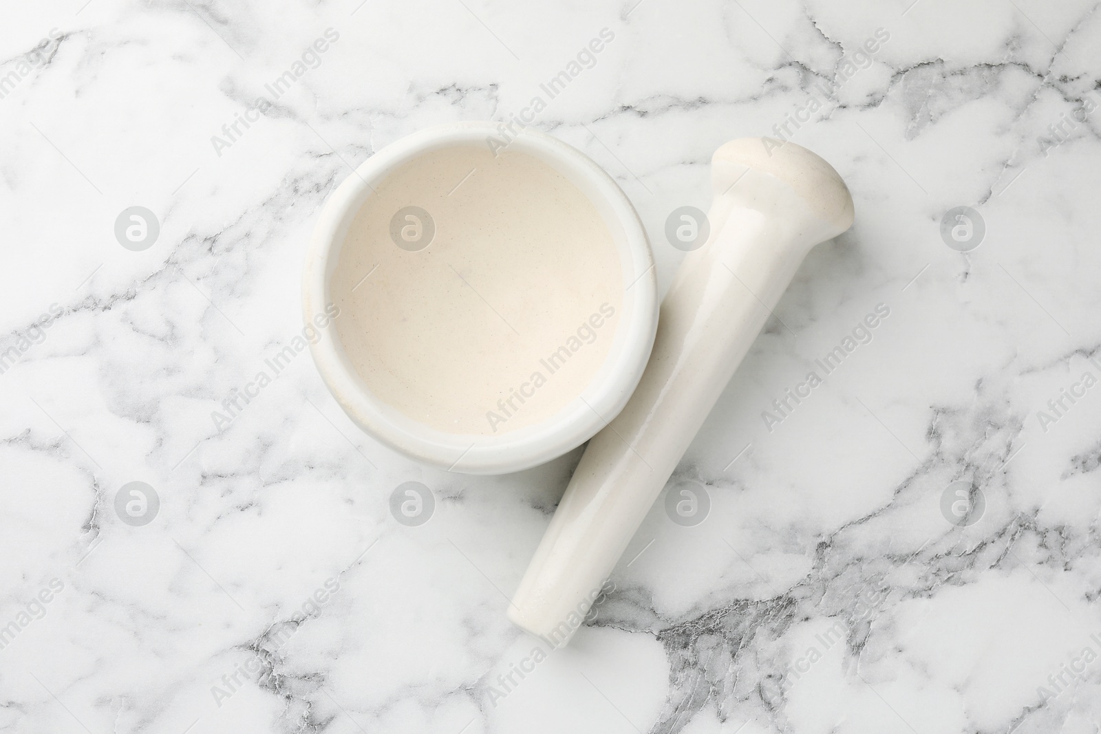 Ceramic mortar and pestle on white marble table, top view Photo of Ceramic mortar and pestle on white marble table, top view