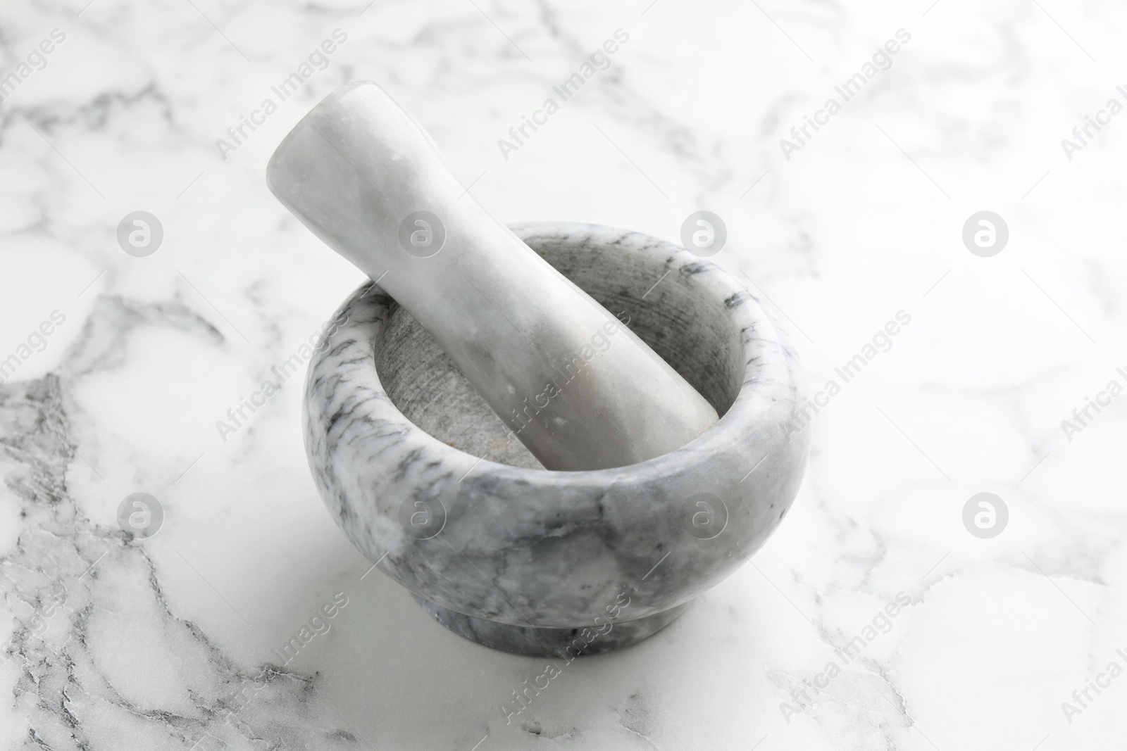 Mortar and pestle on white marble table, closeup Photo of Mortar and pestle on white marble table, closeup