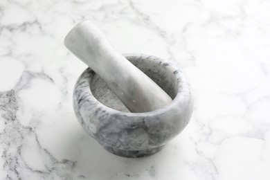 Photo of Mortar and pestle on white marble table, closeup