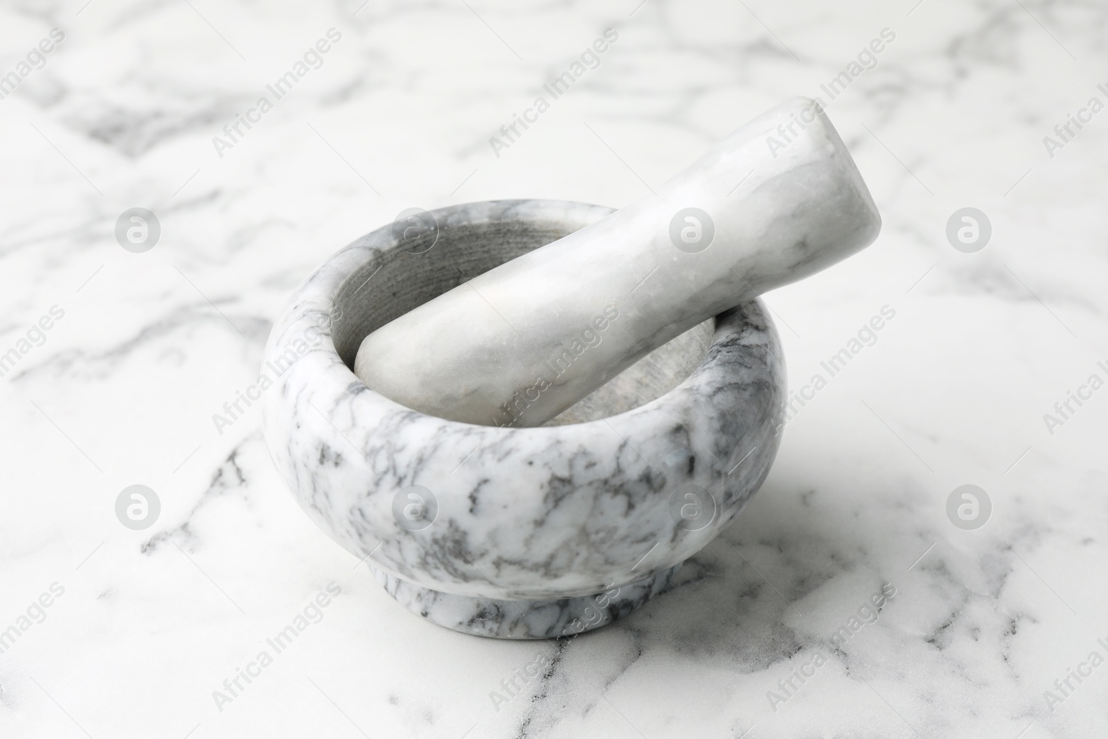 Mortar and pestle on white marble table, closeup Photo of Mortar and pestle on white marble table, closeup