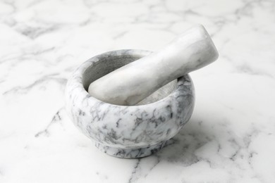 Photo of Mortar and pestle on white marble table, closeup