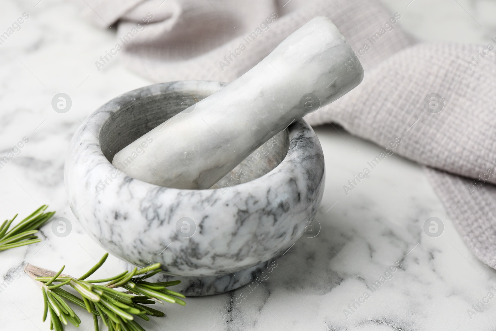 Mortar with rosemary, pestle and cloth on white marble table, closeup Photo of Mortar with rosemary, pestle and cloth on white marble table, closeup