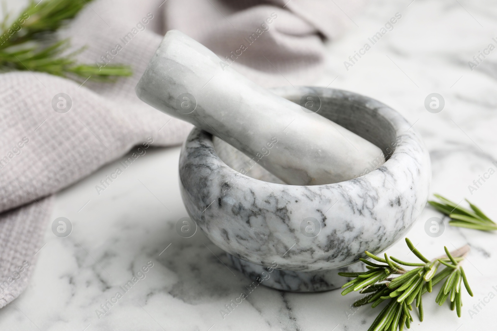 Mortar with rosemary, pestle and cloth on white marble table, closeup Photo of Mortar with rosemary, pestle and cloth on white marble table, closeup