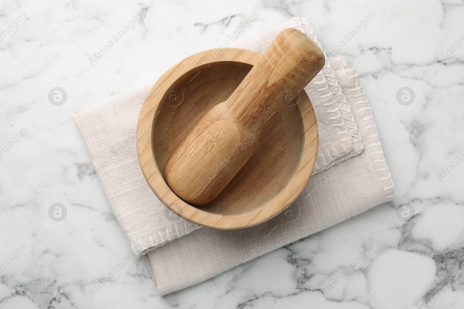 Wooden mortar, pestle and cloth on white marble table, top view Photo of Wooden mortar, pestle and cloth on white marble table, top view