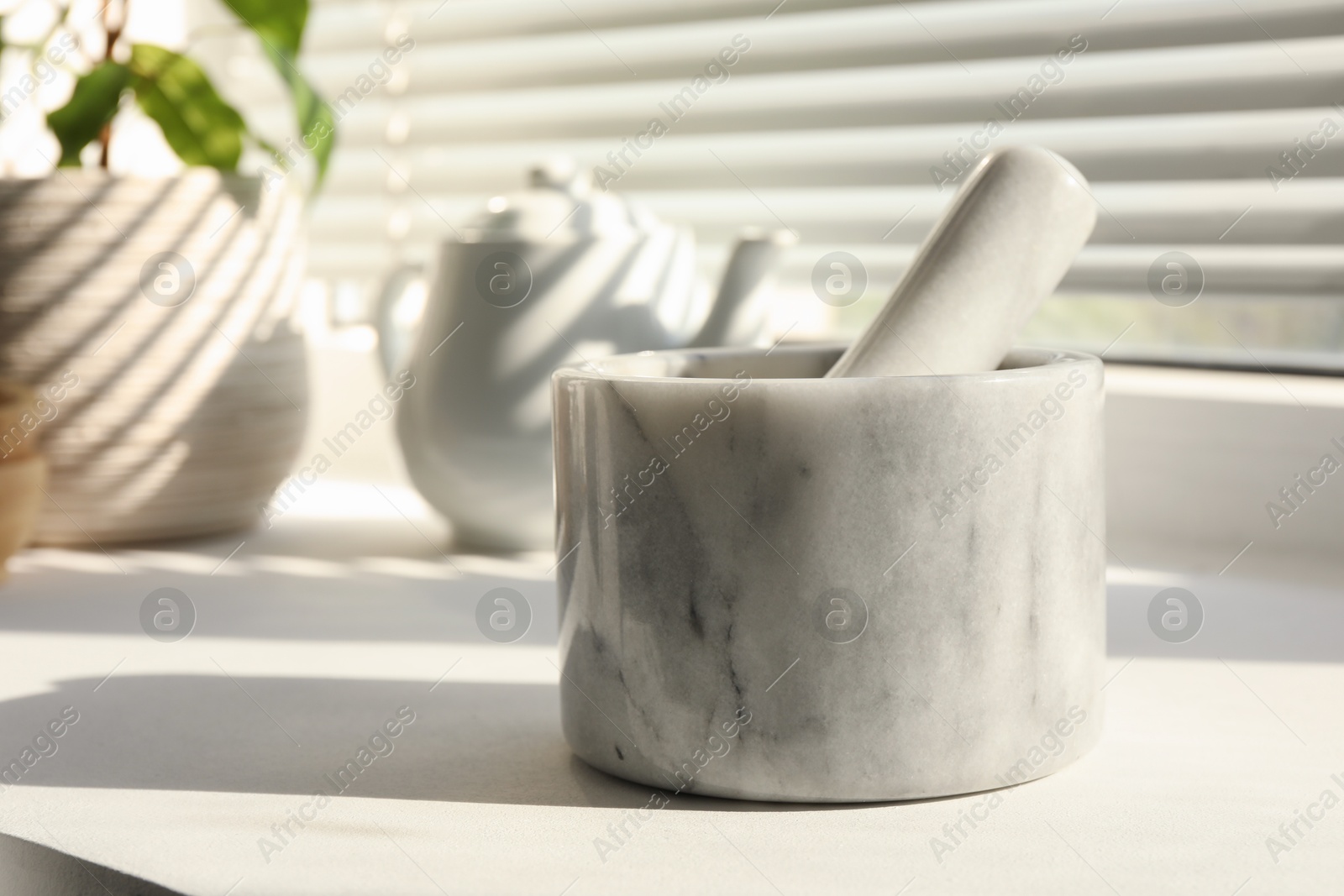 Marble mortar and pestle on windowsill indoors, closeup Photo of Marble mortar and pestle on windowsill indoors, closeup