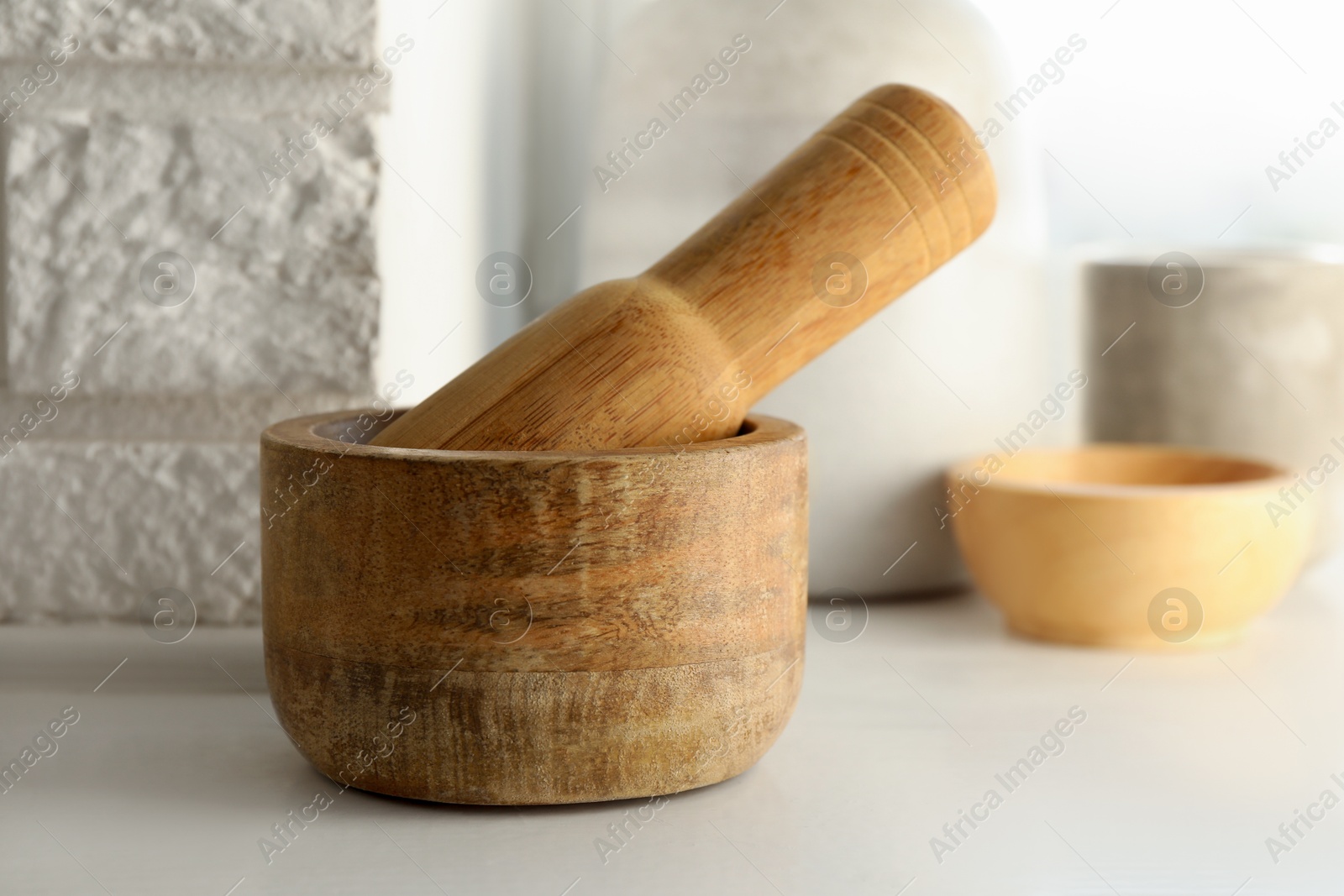 Wooden mortar and pestle on white table indoors, closeup Photo of Wooden mortar and pestle on white table indoors, closeup