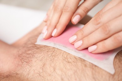 Photo of Young man undergoing wax epilation in salon, closeup