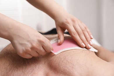 Photo of Young man undergoing wax epilation in salon, closeup