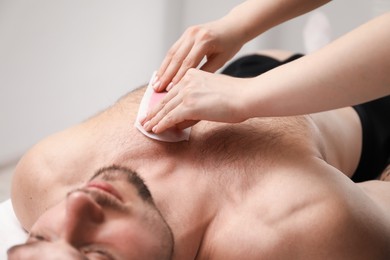 Photo of Young man undergoing wax epilation in salon, closeup