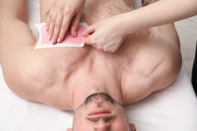 Photo of Young man undergoing wax epilation in salon, closeup