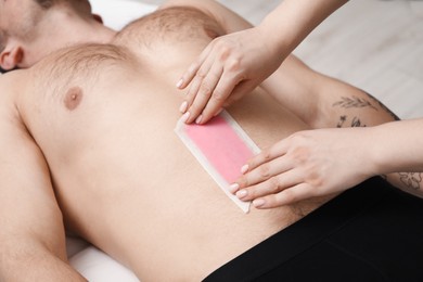 Photo of Young man undergoing wax epilation in salon, closeup